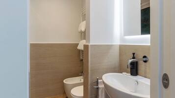Ein modernes Badezimmer mit einer Bidet, Toilette und einem großen Waschbecken mit Spiegel.