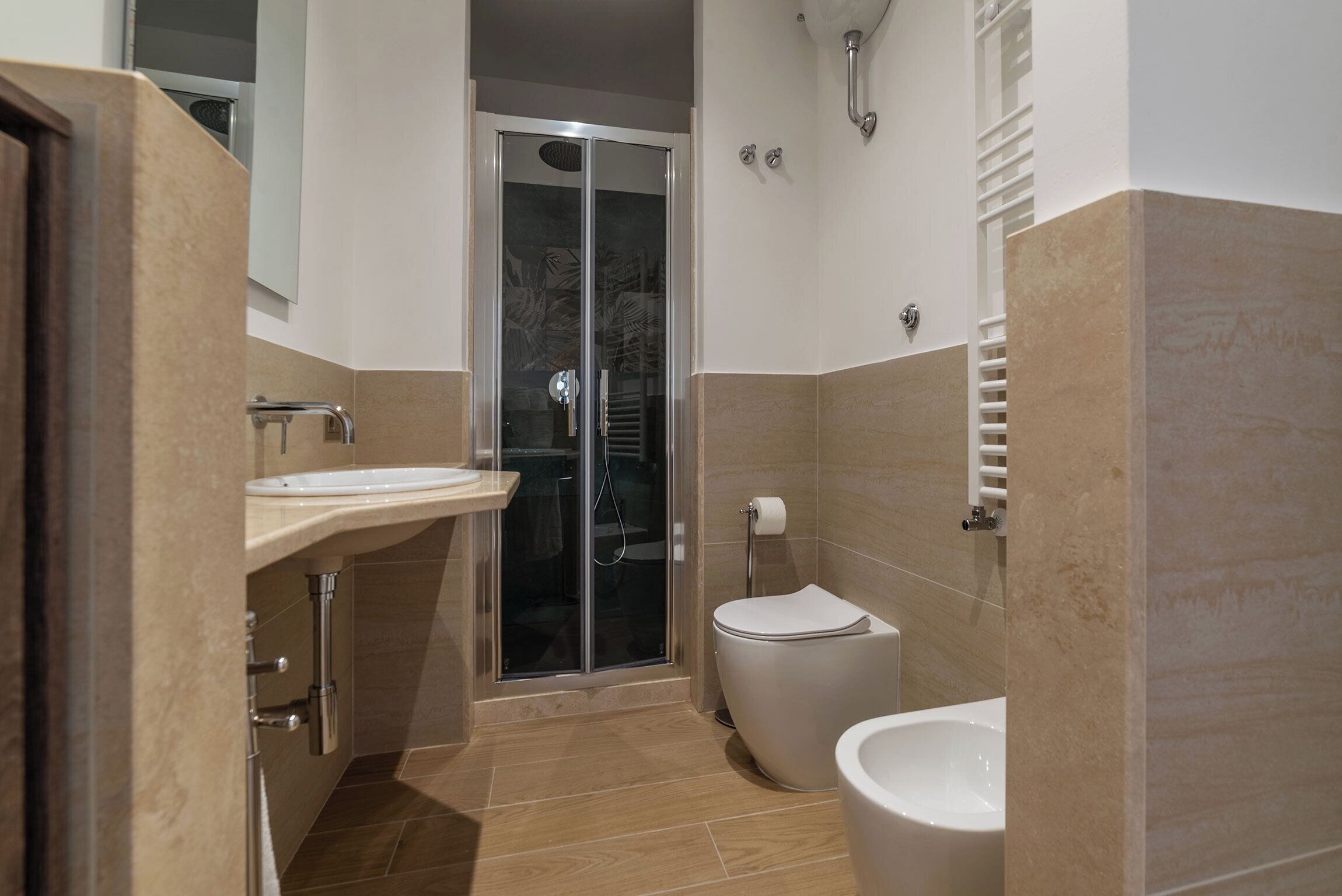 A modern bathroom with a glass shower enclosure, a toilet, and a bidet.