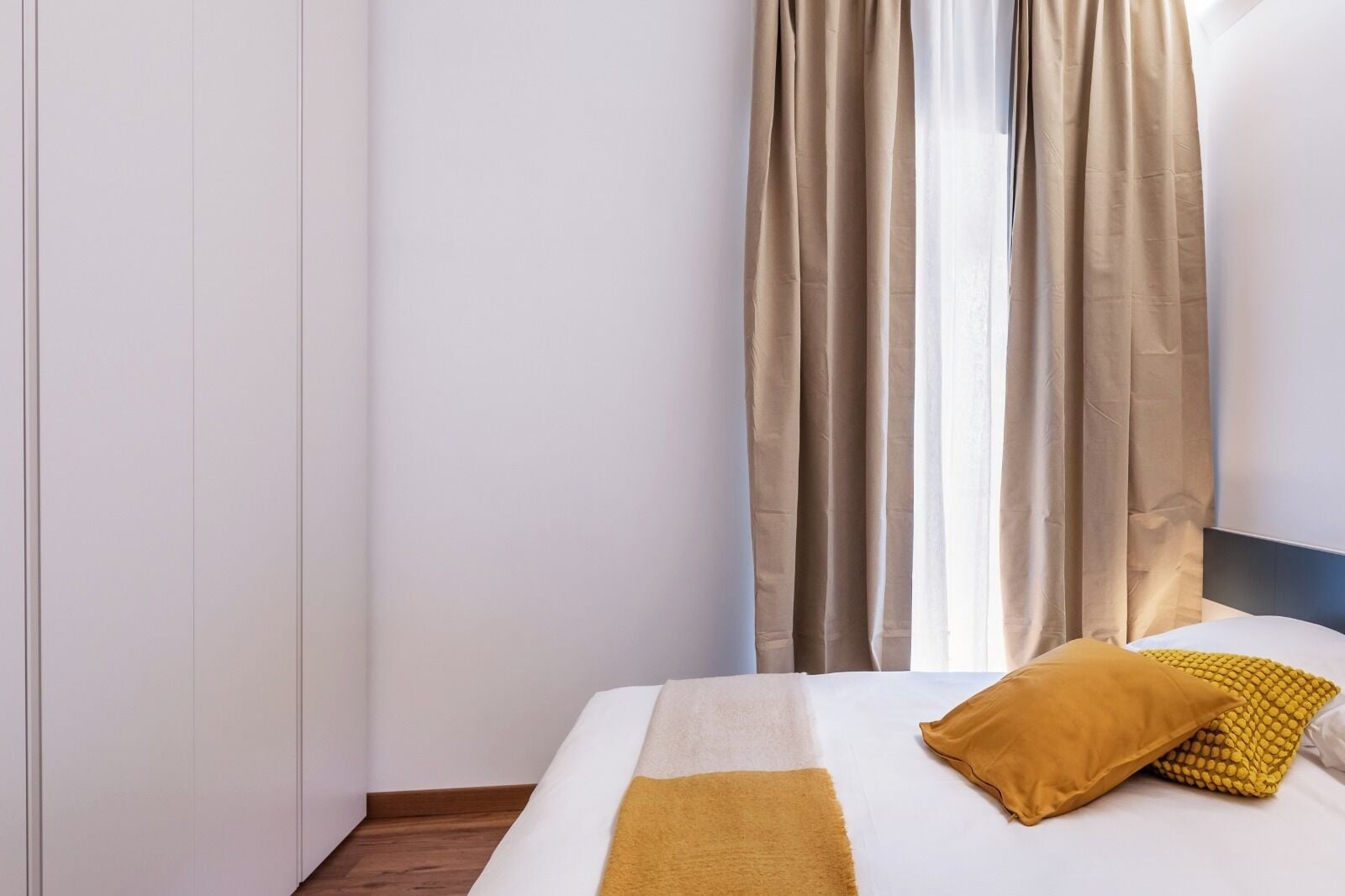 Una habitación de hotel con cama, cabecero y cortinas.