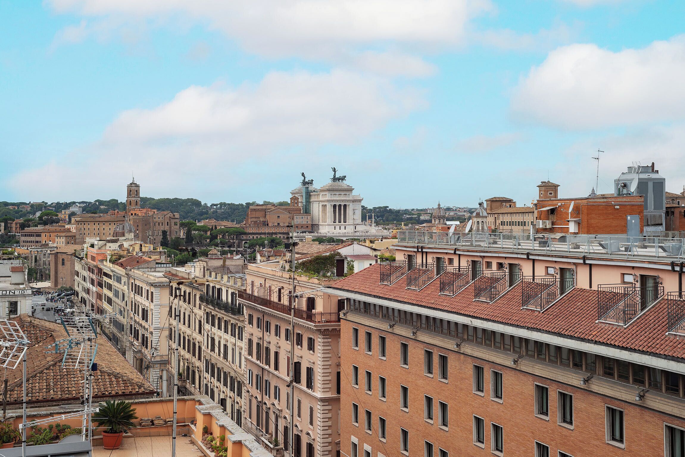 A cityscape with historic buildings, a prominent monument, and a clear sky.