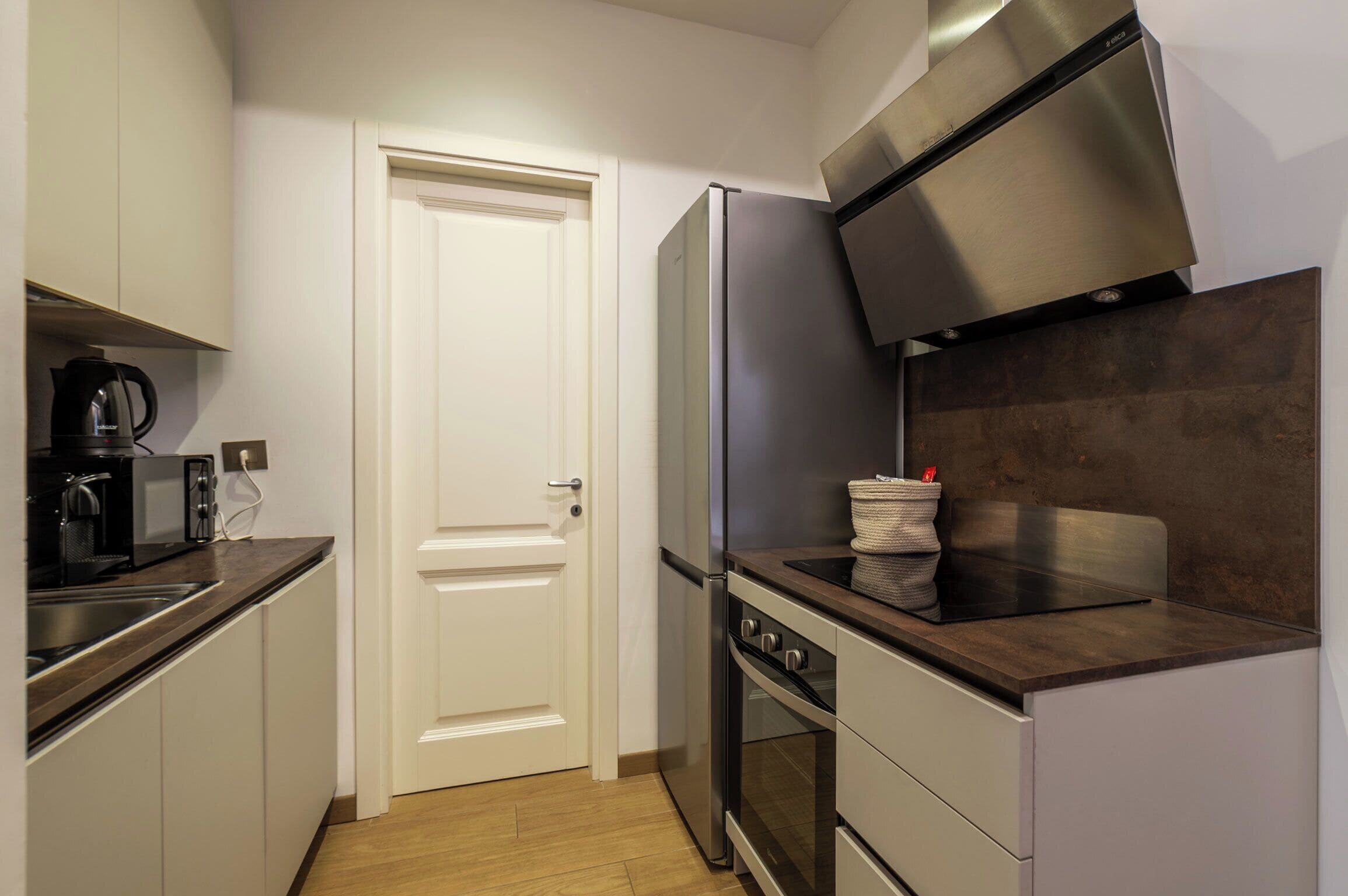 Una cucina compatta con frigorifero in acciaio inossidabile, forno e microonde sul piano di lavoro.