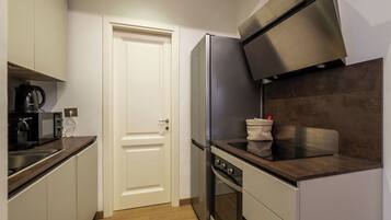 Eine kompakte Küche mit Edelstahl-Kühlschrank, Backofen und Mikrowelle auf der Arbeitsfläche.