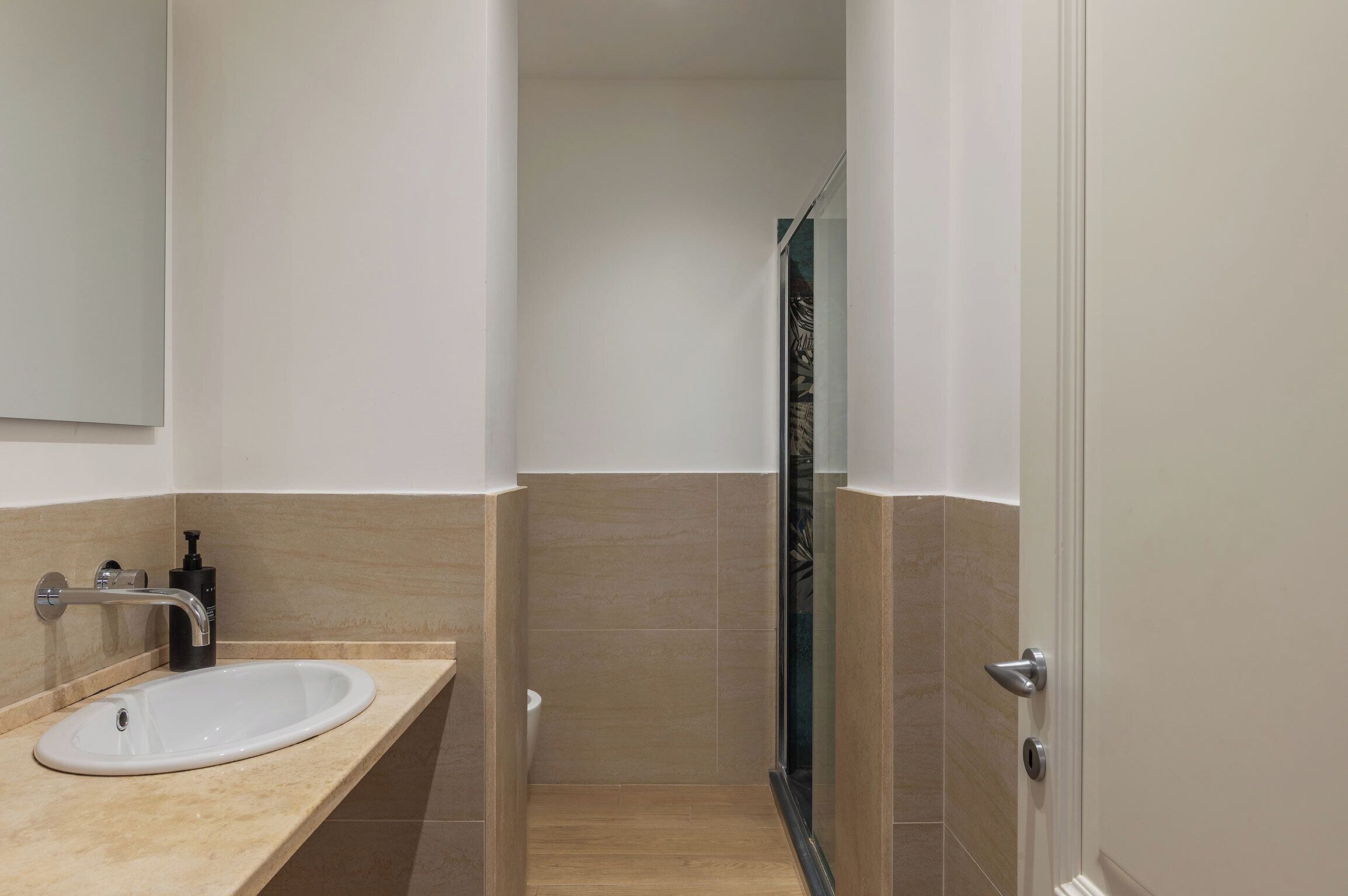 A bathroom with a sink, mirror, and shower.