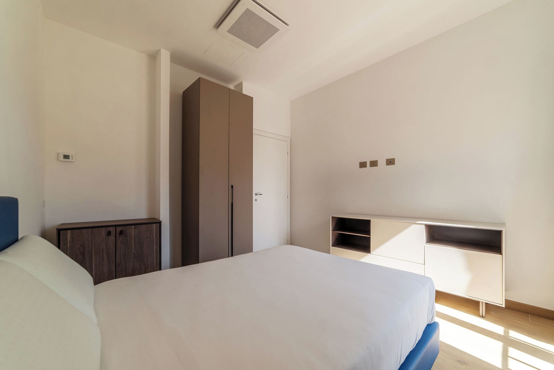 A bedroom with a bed, wardrobe, and built-in TV stand.