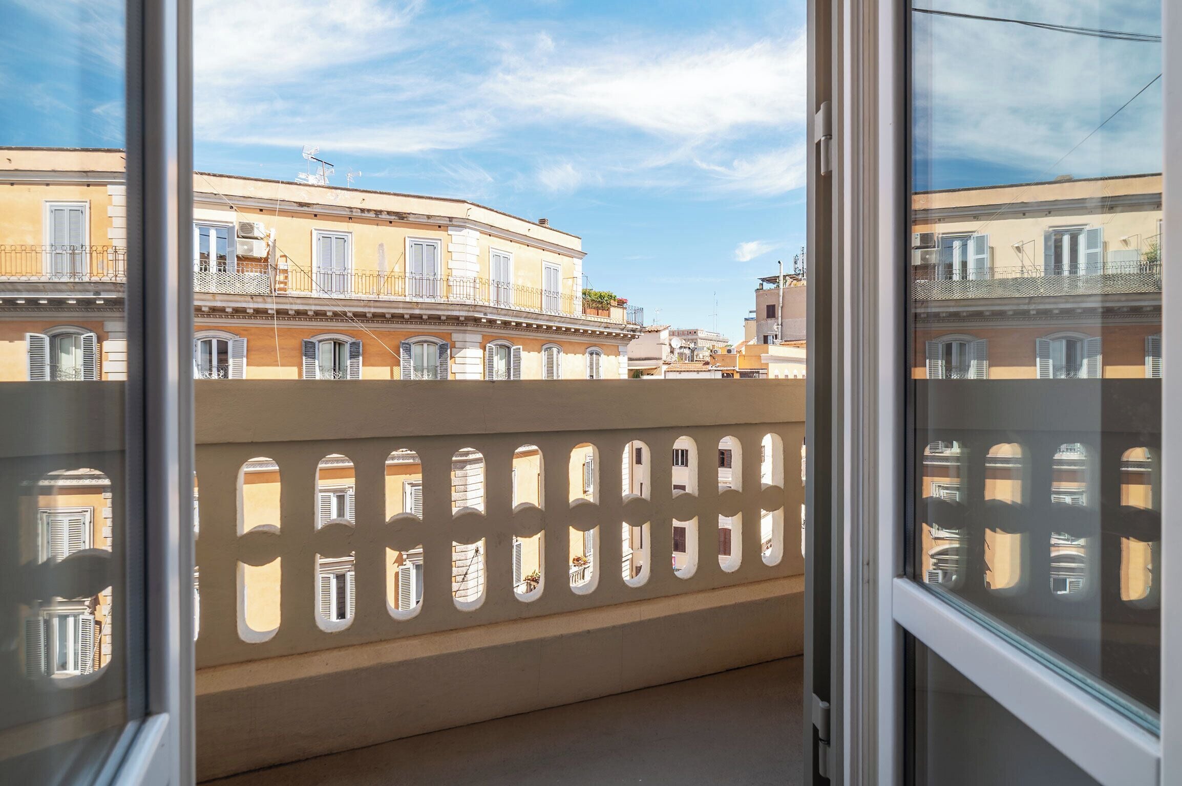 Un balcon offrant une vue sur les immeubles voisins et un ciel dégagé.
