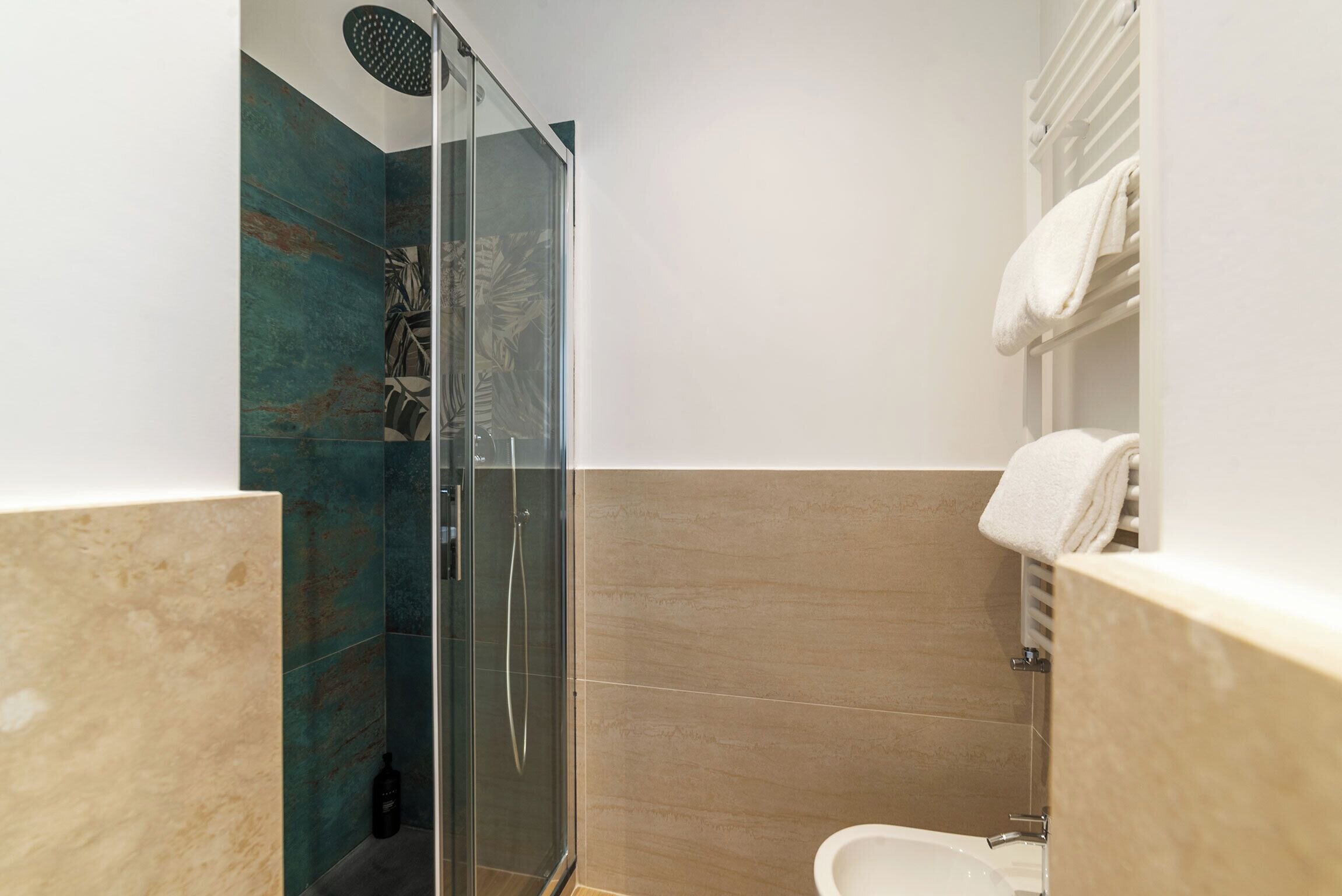 A modern bathroom with a glass shower enclosure, a toilet, and a towel rack.