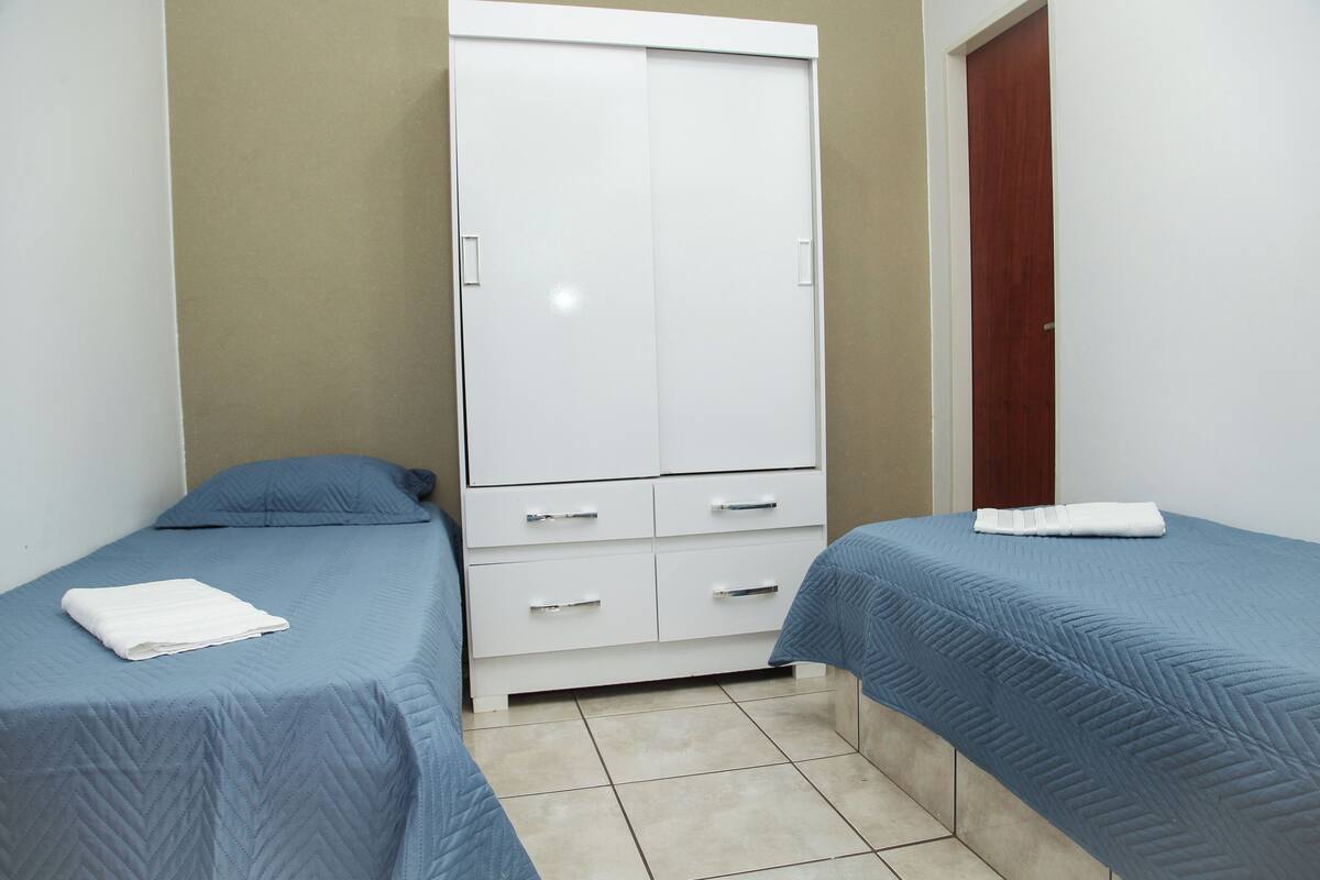 A bedroom with two beds, a wardrobe, and a door.