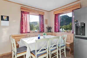 A kitchen with a dining table, chairs, a refrigerator, and a view of a mountain. - Bestefarhaugen - the Cozy House on the Hill,& Dome (Bø)