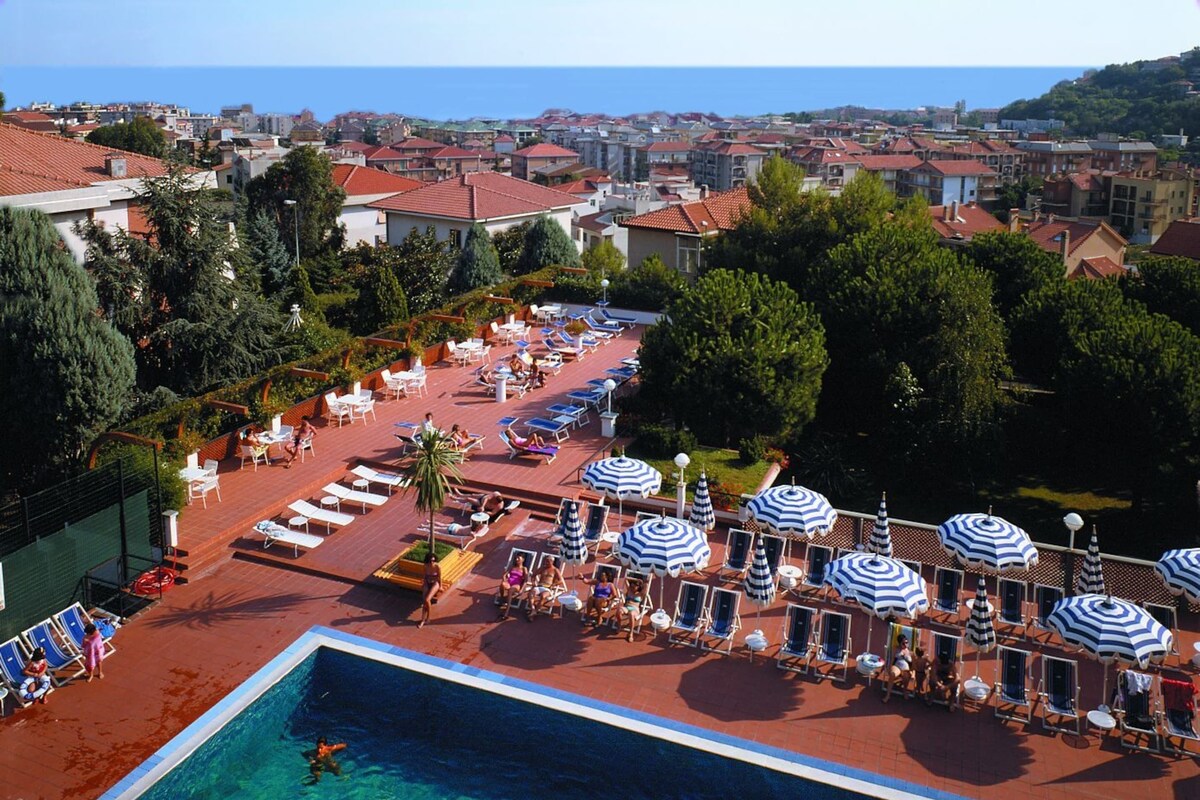 A pool area with clear water, lounge chairs, and umbrellas.