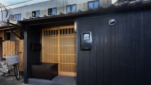 A traditional Japanese gate with a sliding door, a small step leading up to the entrance, and a bicycle parked outside. - Gojo Furusato (Kyoto)