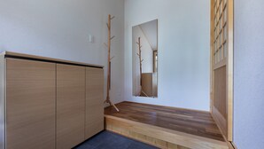 A hallway with wooden flooring, a wooden bench, and a mirror on the wall. - Gojo Furusato (Kyoto)