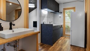 A modern kitchen with a white sink, wooden countertop, and a built-in stove. - Gojo Furusato (Kyoto)