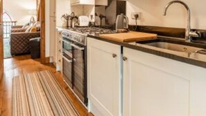 Una cocina moderna con armarios blancos, electrodomésticos de acero inoxidable y encimera de madera.