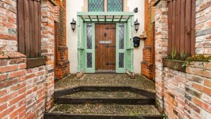 Un edificio tradicional con puerta de madera, contraventanas verdes y fachada de ladrillo.