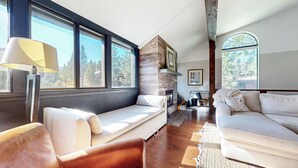 Un salon moderne avec une cheminée en pierre, de grandes fenêtres et un coin salon confortable.