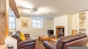 A living room with leather sofas, a television, a fireplace, and a bookshelf. - Host Stay 1 Ruscon Cottage (King's Lynn)