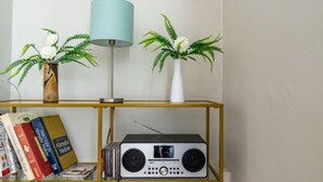 A room with a bookshelf, a radio, and two potted plants.