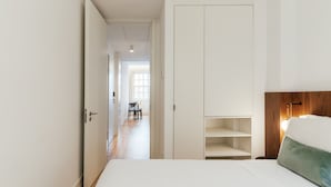 A bedroom with a bed, a nightstand, a wooden headboard, and a closet with shelves.