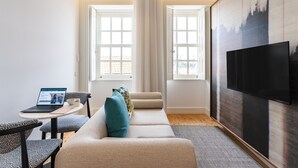 A modern living room with a sofa, a coffee table, a laptop, and a TV.