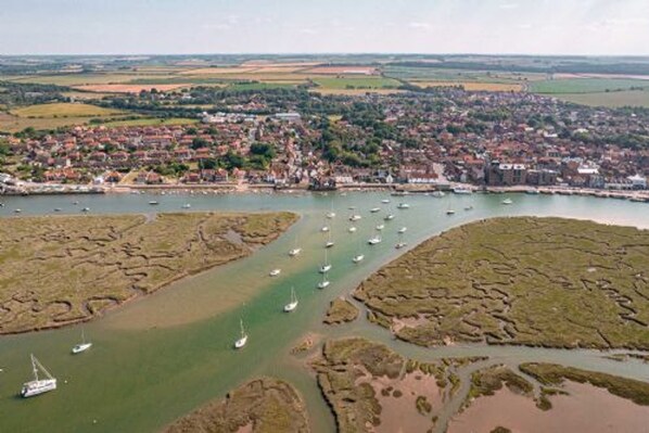 An aerial view of a coastal town with a harbor filled with boats, surrounded by residential areas and fields. - Host Stay The Hideaway (Wells-next-the-Sea)