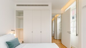 Un dormitorio con una cama, un armario y un pasillo que conduce a otra habitación.