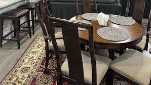 Un comedor con una mesa redonda, sillas y un televisor colgado en la pared.