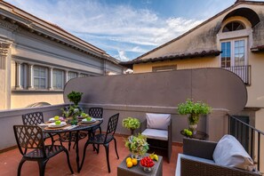 Eine Terrassengaststätte mit Esstisch, umgeben von Korbmöbeln und Blumentöpfen.