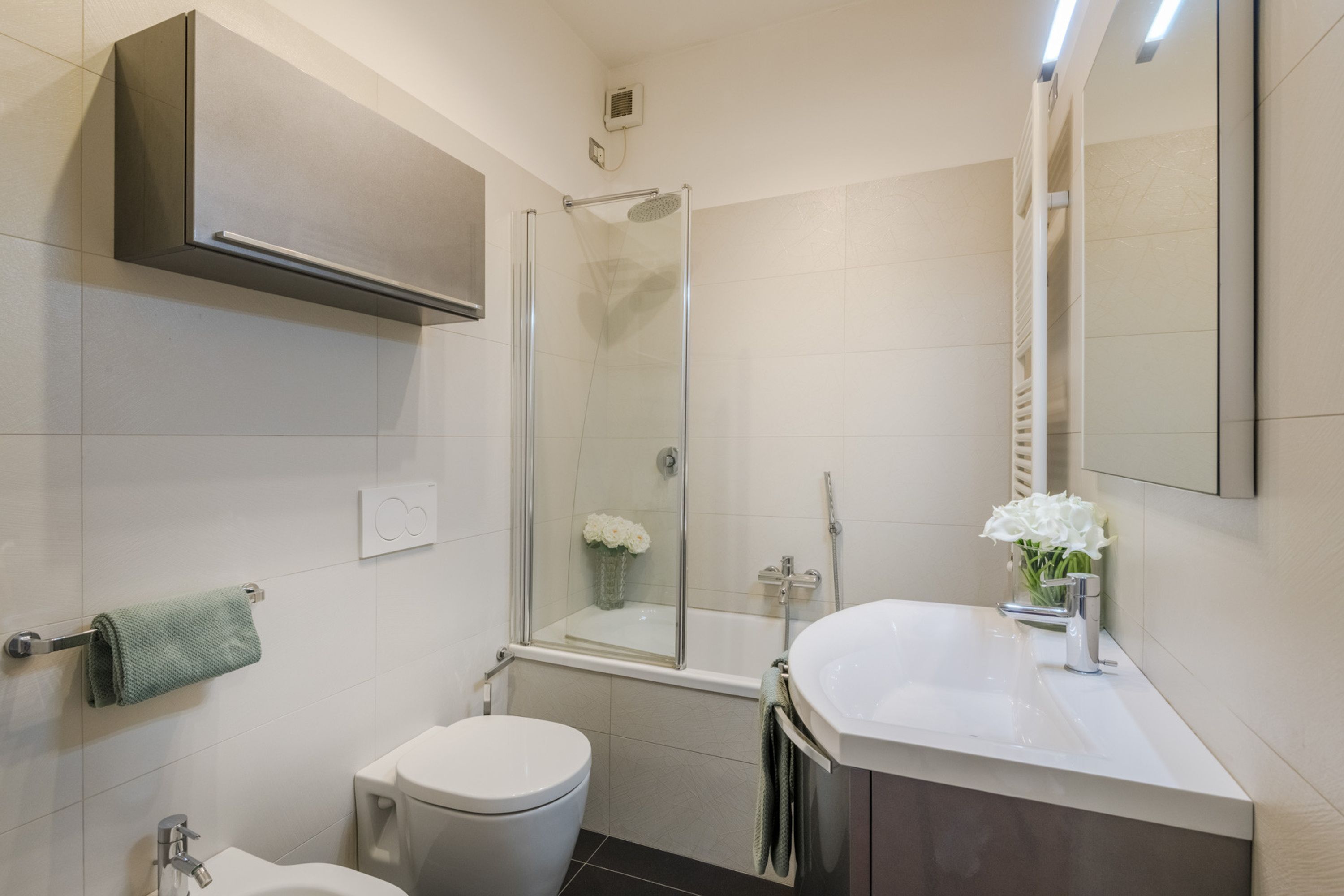 A modern bathroom with a glass-enclosed shower, a white toilet, a sink with a mirror, and a towel rack.
