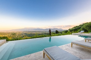 Una piscina a sfioro con vista sulla città e sulle montagne.