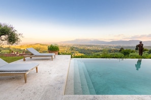 Una piscina a sfioro con vista panoramica su una città e montagne sullo sfondo.
