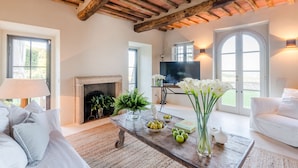 Amplia sala de estar con chimenea, televisor y un ventanal.