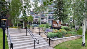 A residential building with a sign reading 'VAIL SPA CONDOMINIUMS,' a set of outdoor stairs, and a landscaped garden area.