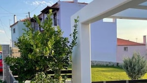 A modern building with a white facade, a balcony with a metal railing, and a view of a green landscape. - Villa Evanthia (Avlonárion)