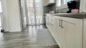 A modern kitchen with white cabinets, a stainless steel refrigerator, and a coffee maker on the counter. - Villa Evanthia (Avlonárion)