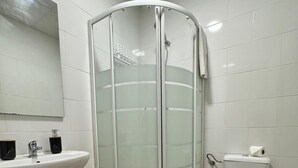 A bathroom with a glass shower enclosure, a white sink, and a toilet. - dubai resort (Ponteareas)