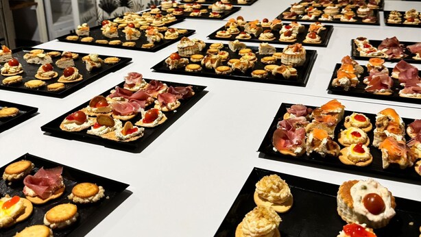 A buffet table with various appetizers, including canapés, cheese, and meat options, arranged on black plates. - dubai resort (Ponteareas)