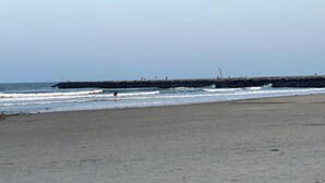 Ein Strand mit einem steinernen Wellenbrecher und brechenden Wellen.
