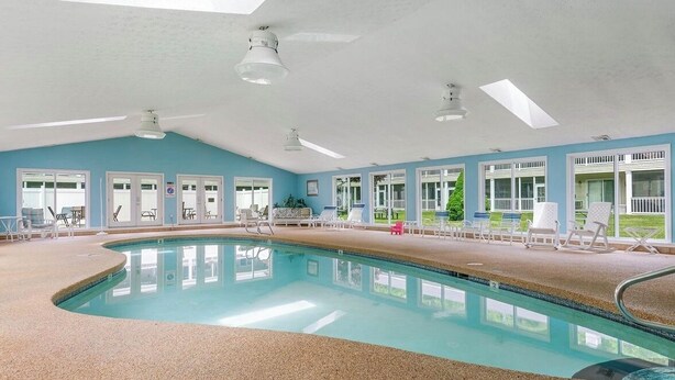 Ein Innenpool mit klarem, blauem Wasser, umgeben von Liegestühlen und einer Dachkuppel.
