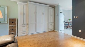 Ein geräumiges Zimmer mit großem weißen Kleiderschrank, einem Ledersofa und einem Deckenventilator.