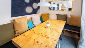 A modern living space with a wooden dining table, a sofa with cushions, a blue abstract painting, and a mirror with lights. - Terrace | Parking | Great for Couples | Sleeps 7 (Bristol)