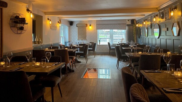 A restaurant interior with wooden tables, chairs, and a central walkway. - The Suffolk Hotel (Haverhill)