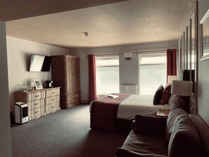 A bedroom with a bed, a wardrobe, a desk, a television, and a window. - The Suffolk Hotel (Haverhill)