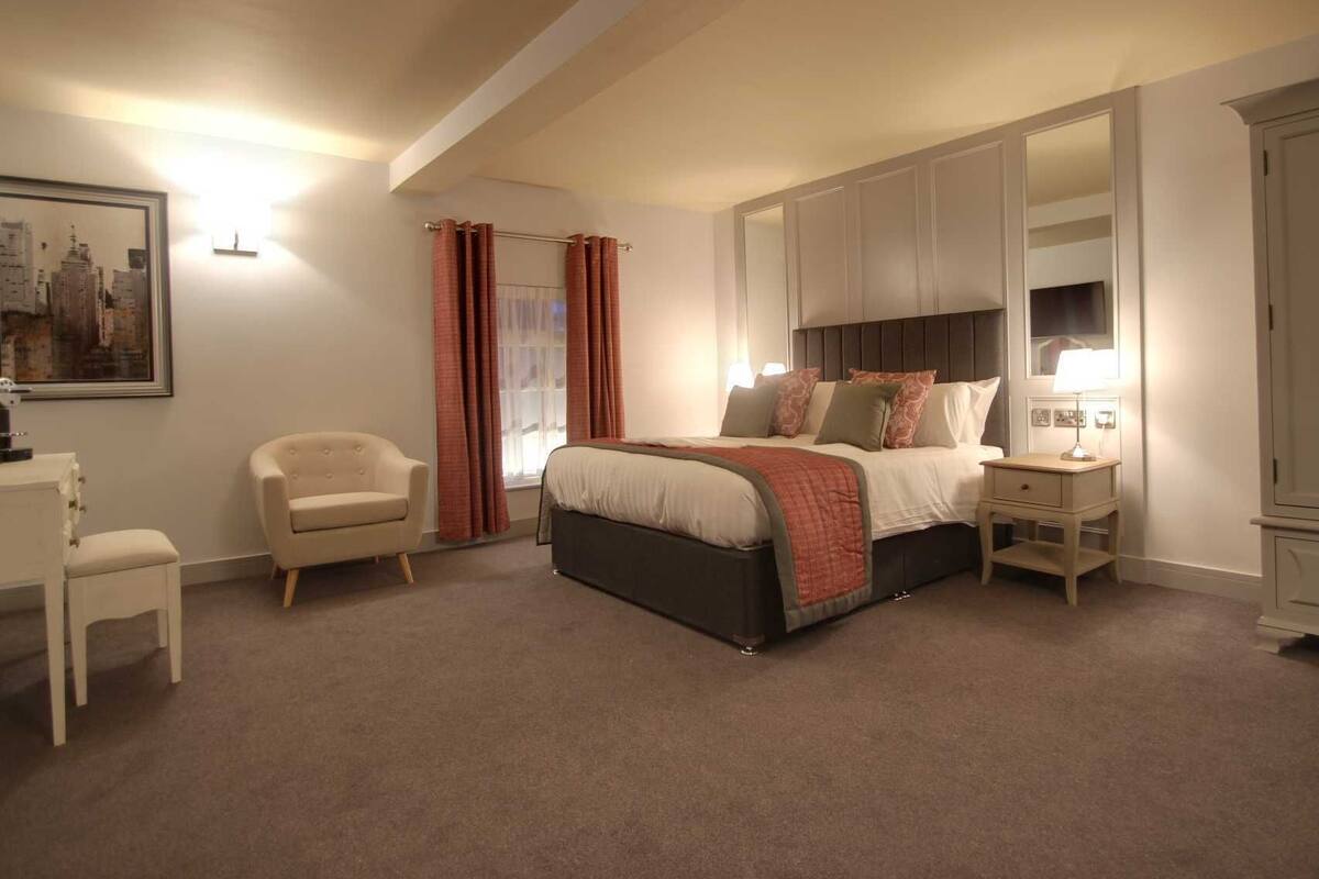 A bedroom with a bed, a chair, a desk, and a wardrobe.