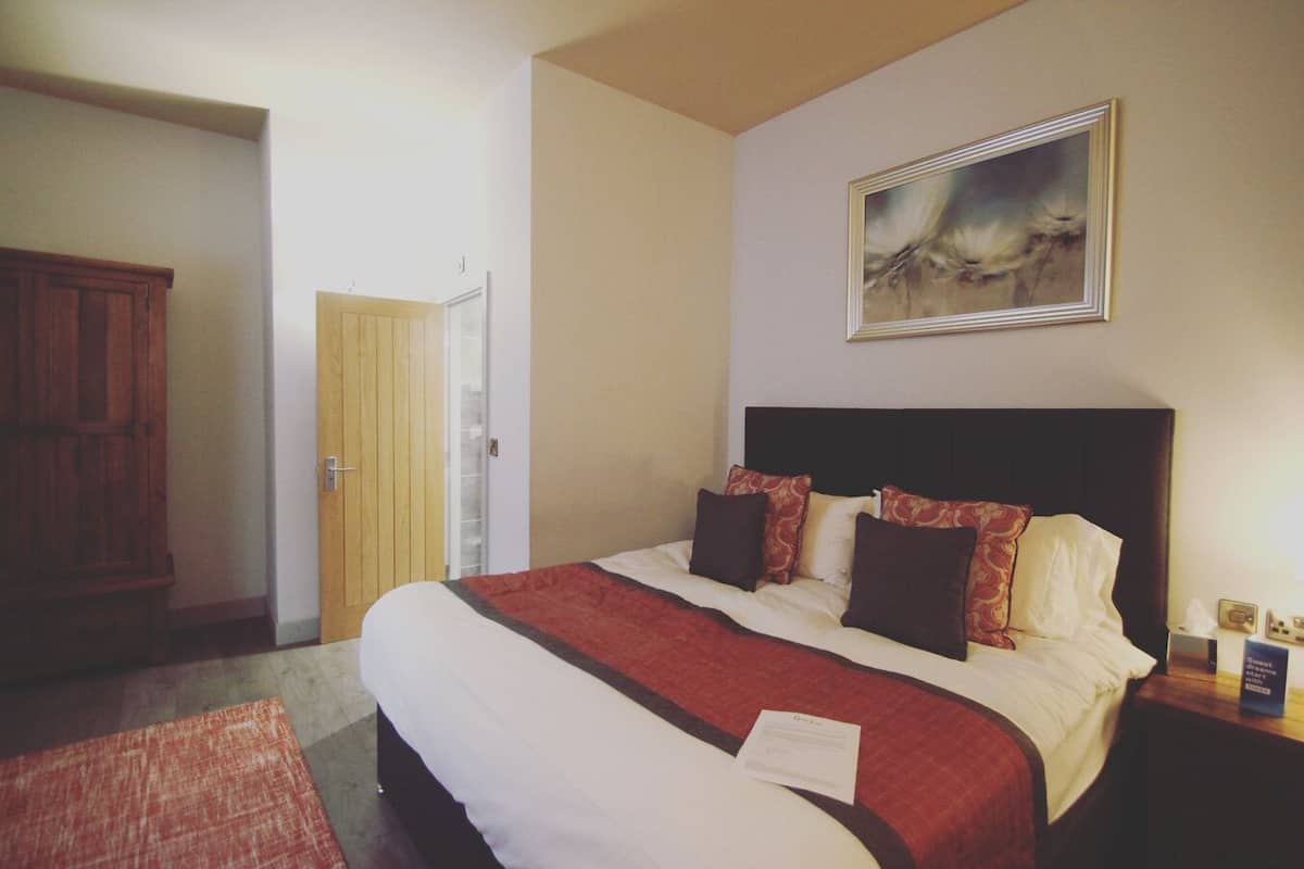 Relax in a spacious room with a large bed, a wardrobe, and a door leading to an adjacent room.