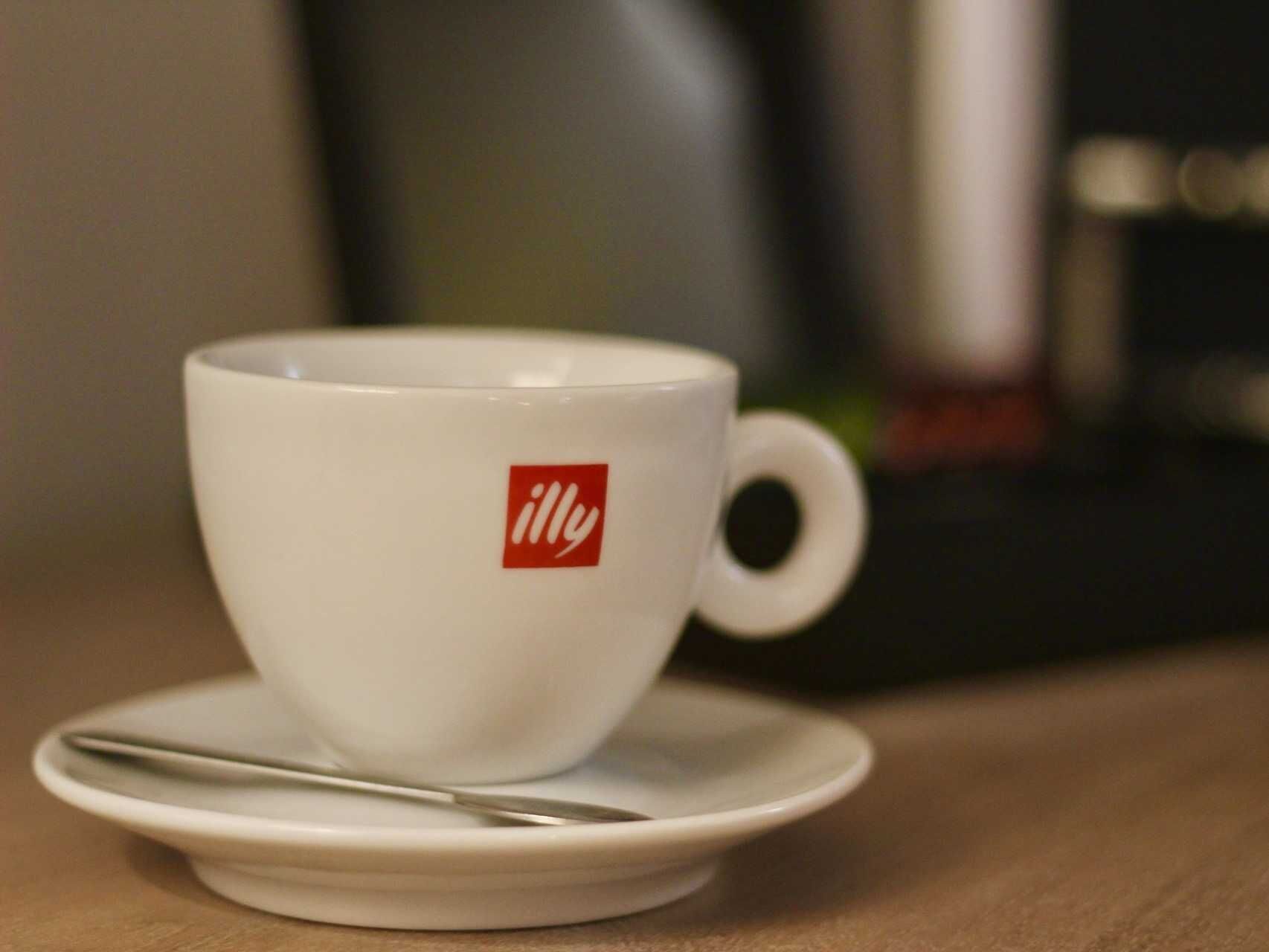Una taza blanca con asa y un plato sobre una mesa de madera.