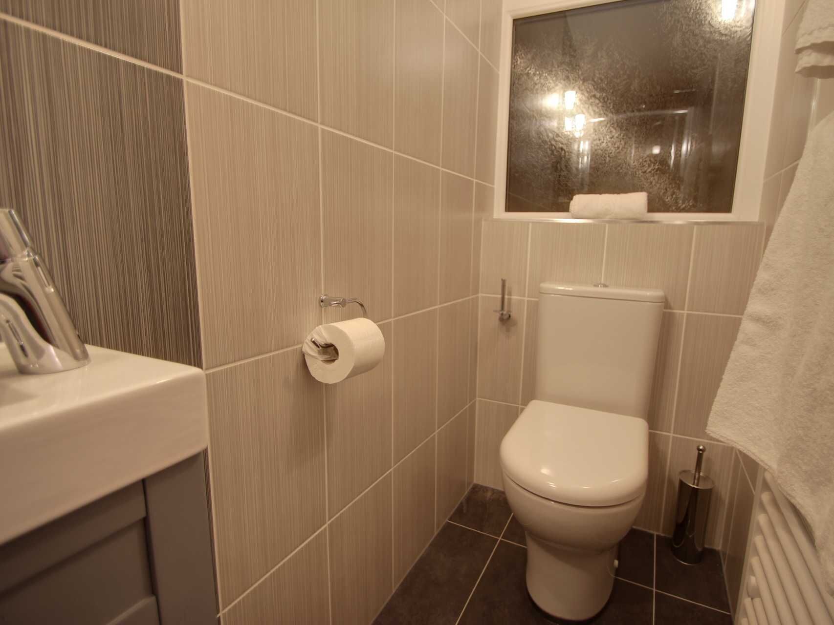 Ein kleines, modernes Badezimmer mit Toilette, Handtuchhalter und Toilettenpapierhalter.