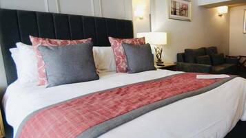 Una habitación de hotel con una cama grande, cabecera negra y sofá gris.