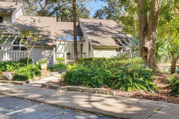 A two-story house with a front porch, a small garden, and a driveway. - Townhome on Golf Course in Shipyard Plantation (Hilton Head Island)