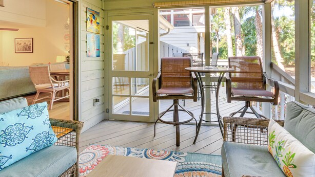 A covered porch with wicker furniture, a dining table, and a view of the backyard.