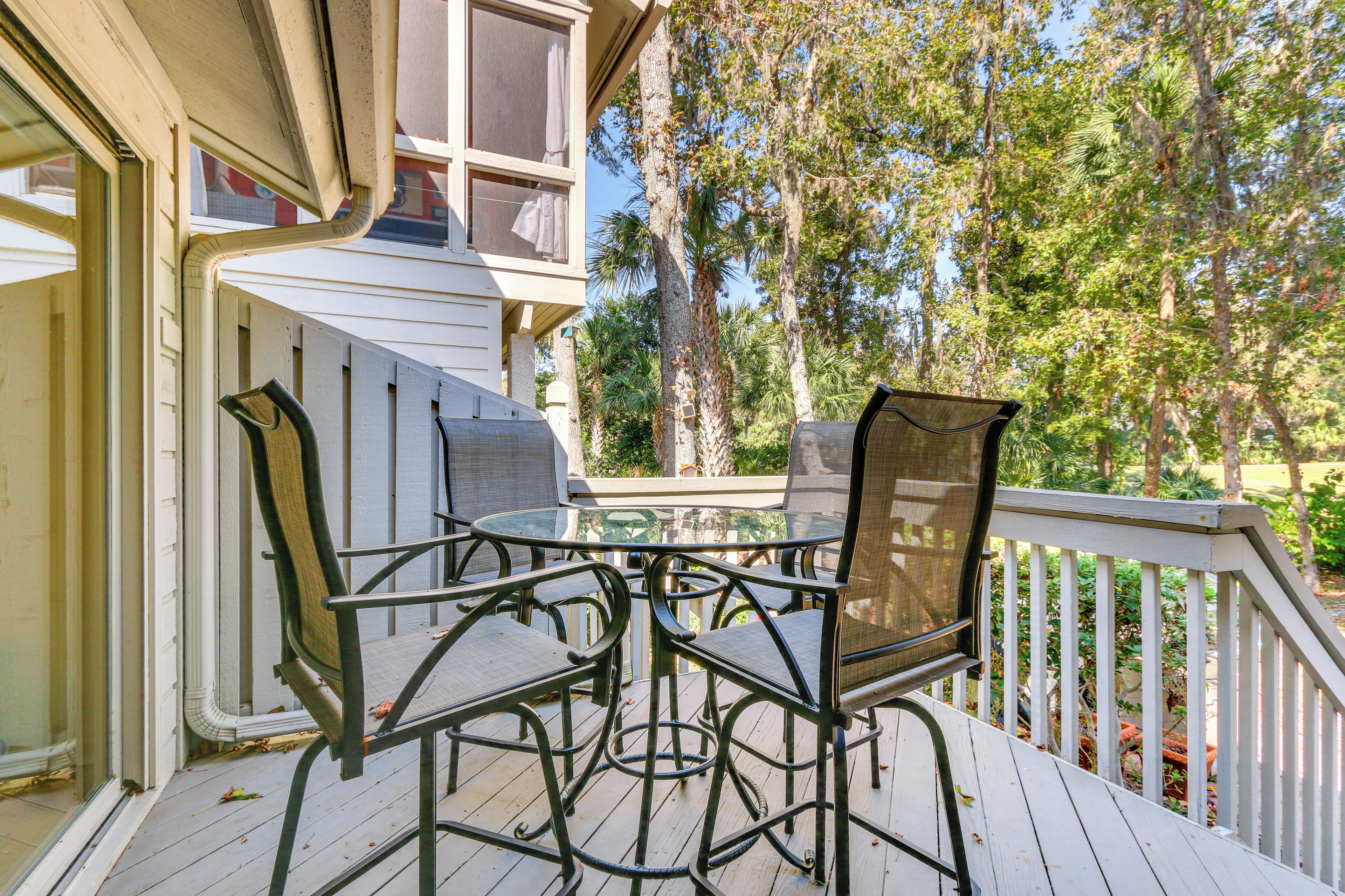 A deck with a glass-top table and four chairs.